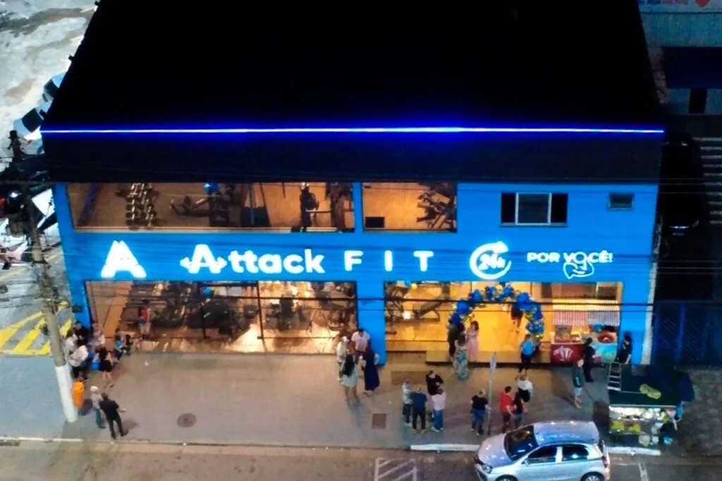 Fachada azul iluminada da Attack Fit à noite