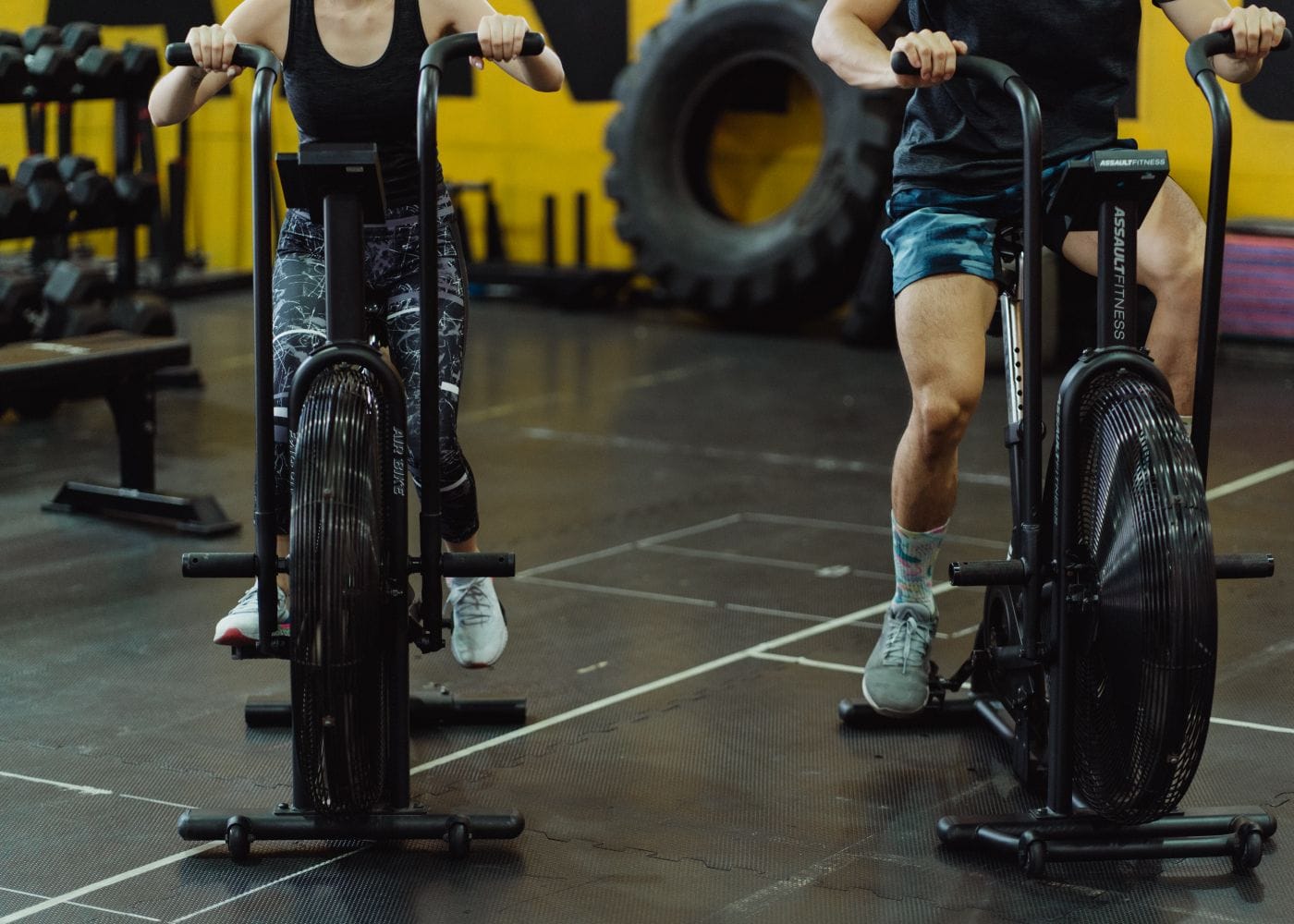 Duas pessoas pedalando bicicletas de treino lado a lado